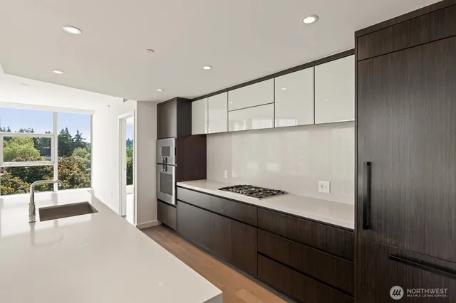 a kitchen with stainless steel appliances kitchen island granite countertop a refrigerator a stove and a sink with wooden floor