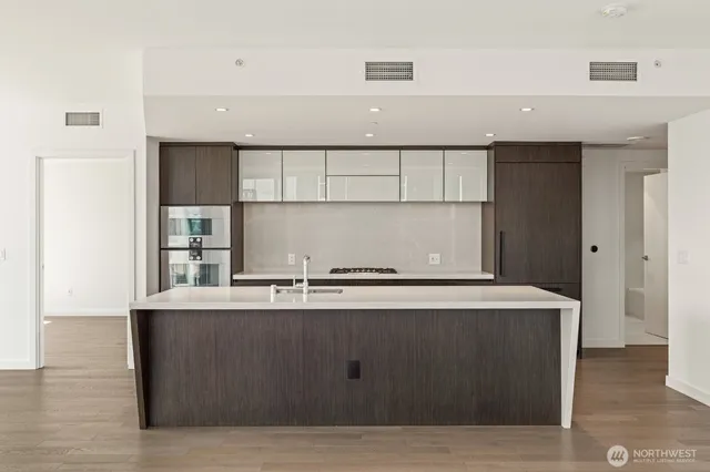 a living room with stainless steel appliances kitchen island sink and wooden floor