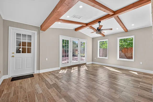 a view of an empty room with wooden floor and a window