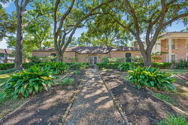 a view of a yard in front of a house with large trees