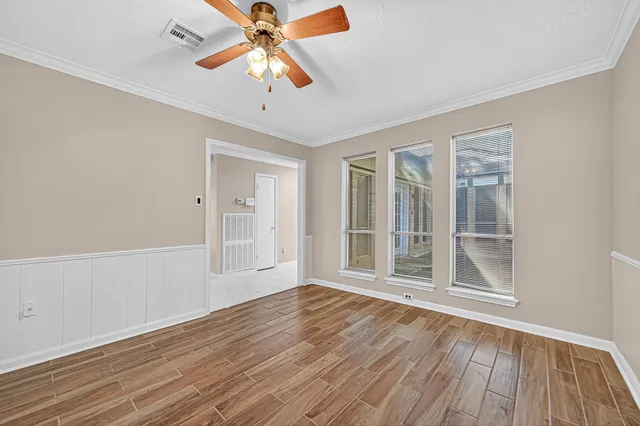 a view of an empty room with wooden floor and a window