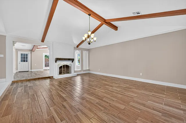 a view of empty room with fireplace and wooden floor