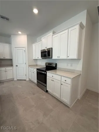 a kitchen with granite countertop white cabinets and stainless steel appliances