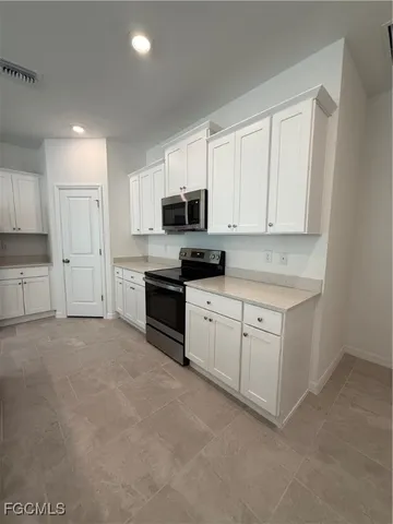 a kitchen with granite countertop white cabinets and stainless steel appliances