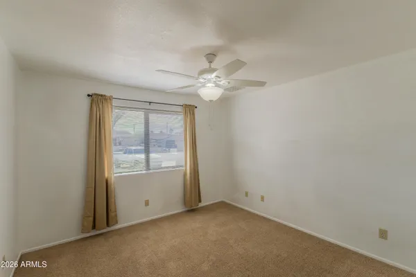 an empty room with windows and ceiling fan