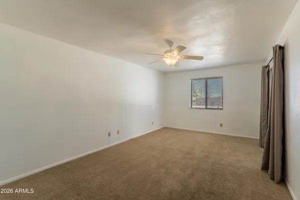 an empty room with windows and fan