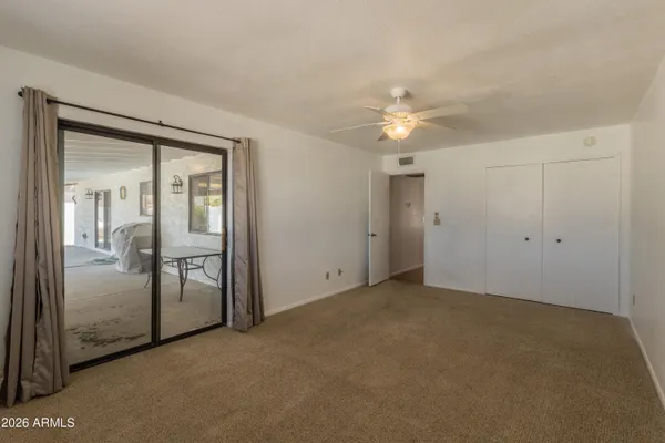 an empty room with chandelier fan and glass door