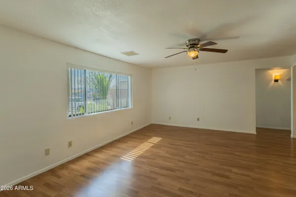 a view of empty room with wooden floor and fan