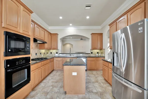 a kitchen with stainless steel appliances granite countertop a sink a stove and a refrigerator