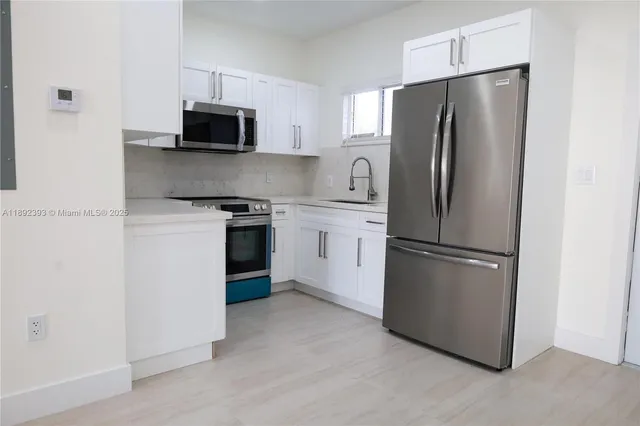 a kitchen with stainless steel appliances white cabinets and a refrigerator