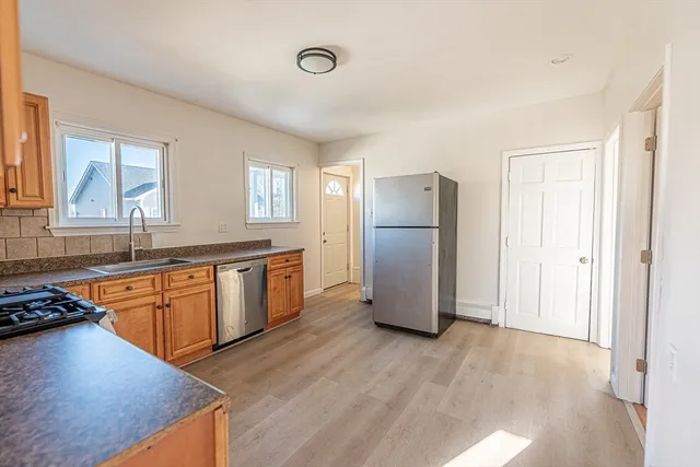 a kitchen with stainless steel appliances granite countertop a refrigerator a stove a sink and a refrigerator with wooden floors