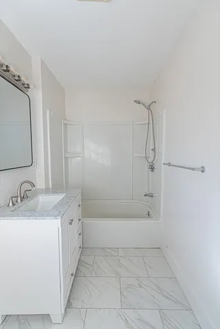 a bathroom with a granite countertop sink a mirror and shower