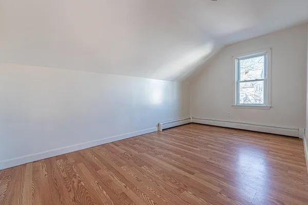 a view of an empty room with wooden floor and window