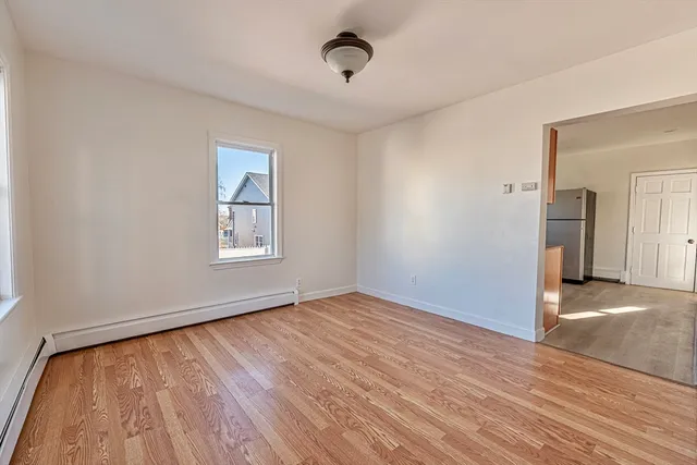 a view of an empty room with window and wooden floor