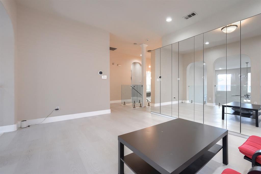 2246 Longview Road Irving, TX 75063 - Photo 26 of 40 Open concept living space featuring light wood-finish flooring, a wall of reflective panels, and a glass-paneled railing