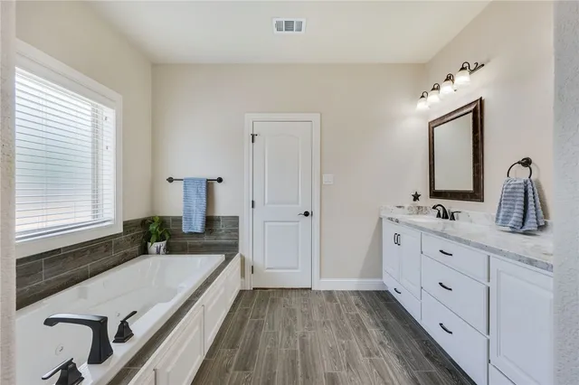 a spacious bathroom with a granite countertop sink mirror and bathtub