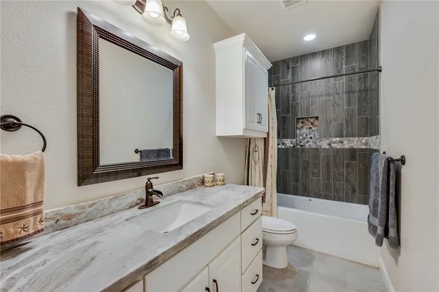 a bathroom with a granite countertop sink a toilet and shower
