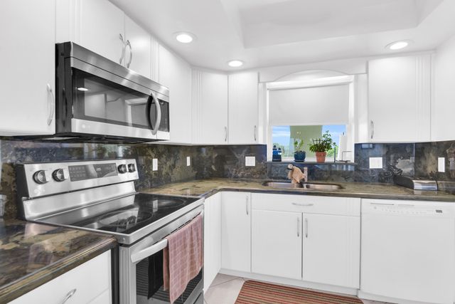 a kitchen with granite countertop a sink stove and cabinets