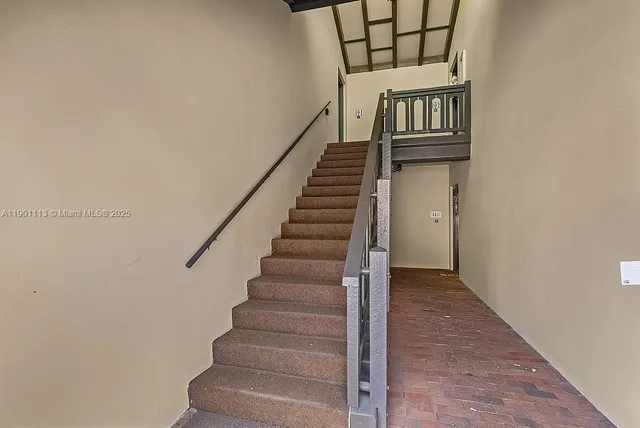 a view of staircase with railing and white walls