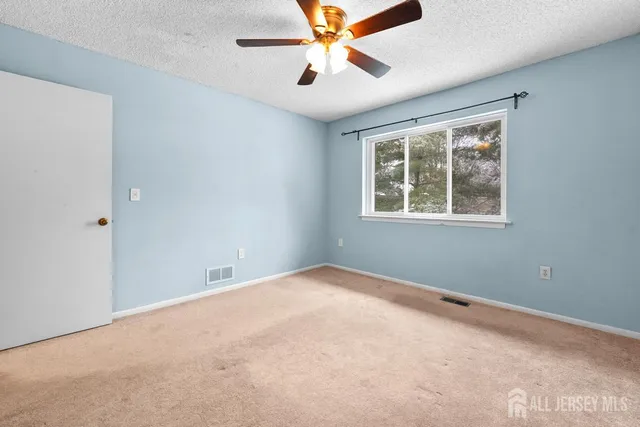 an empty room with windows and fan