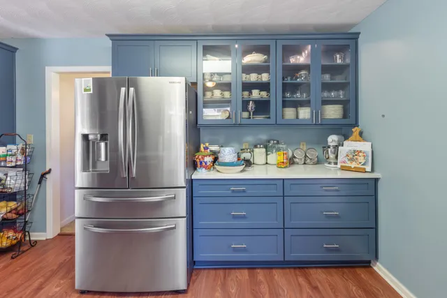 a kitchen with a refrigerator and wooden floor
