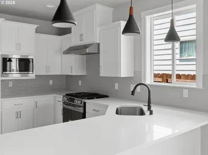 a kitchen with stainless steel appliances a sink a stove and a wooden floors