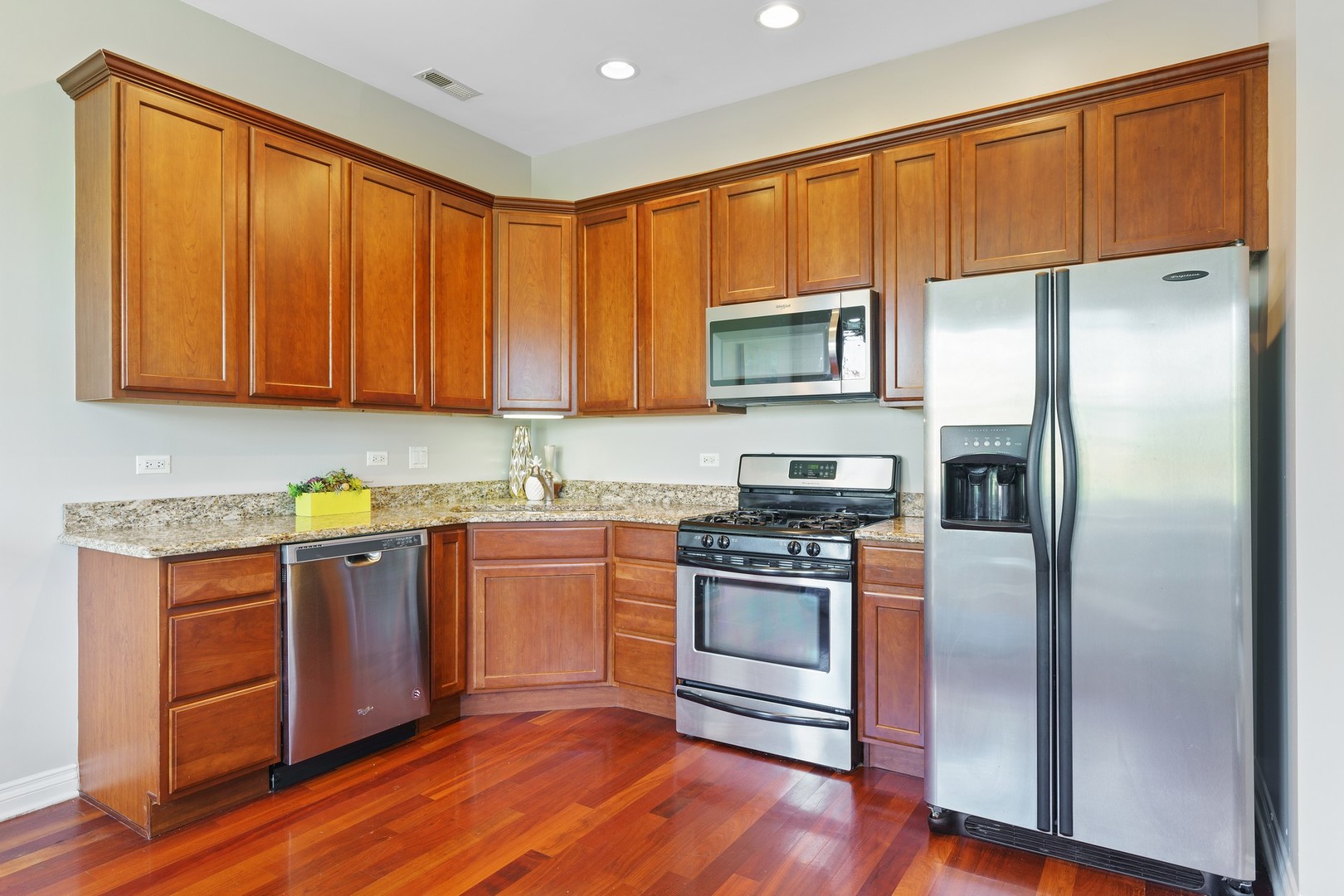 4440 North Dover Street, Unit 3S Chicago, IL 60640 - Photo 6 of 20 a kitchen with granite countertop wooden floors stainless steel appliances and a sink