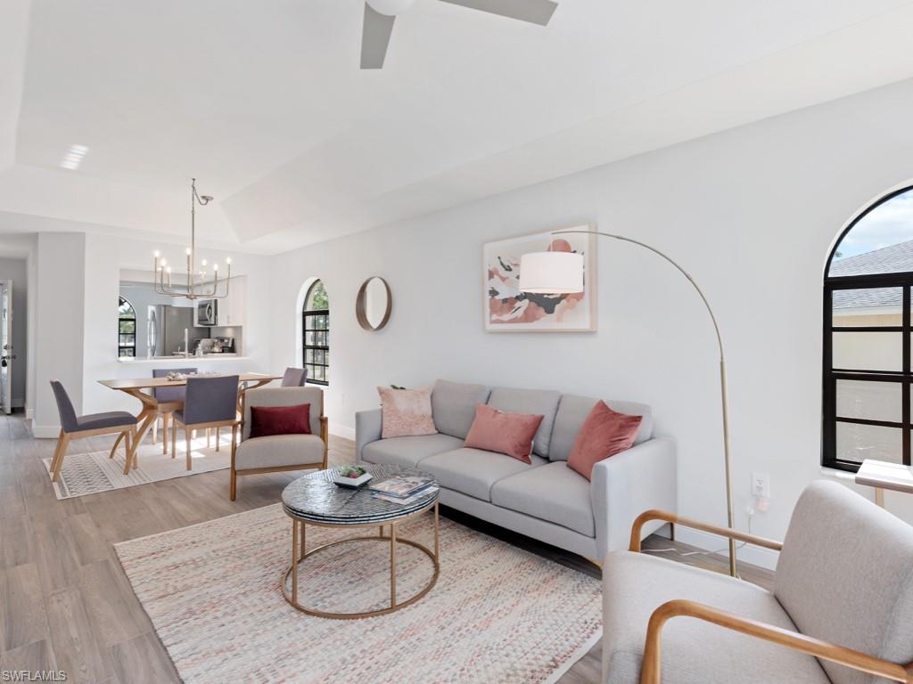 709 Augusta Boulevard, Unit 7095 Naples, FL 34113 - Photo 4 of 16 Living room featuring vaulted ceiling, hardwood / wood-style floors, plenty of natural light, and ceiling fan with notable chandelier