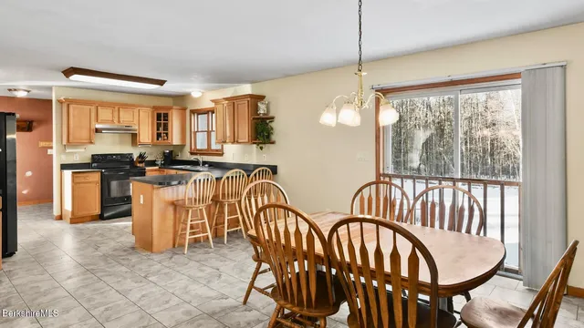 a kitchen with stainless steel appliances granite countertop a stove a sink a dining table and chairs