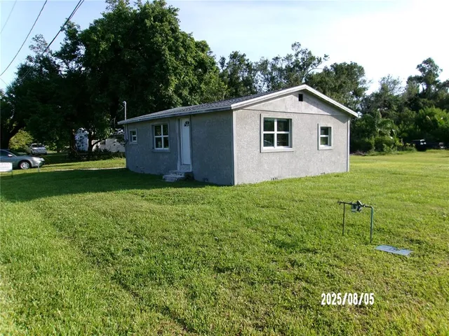 a view of a yard in front of a house with large trees