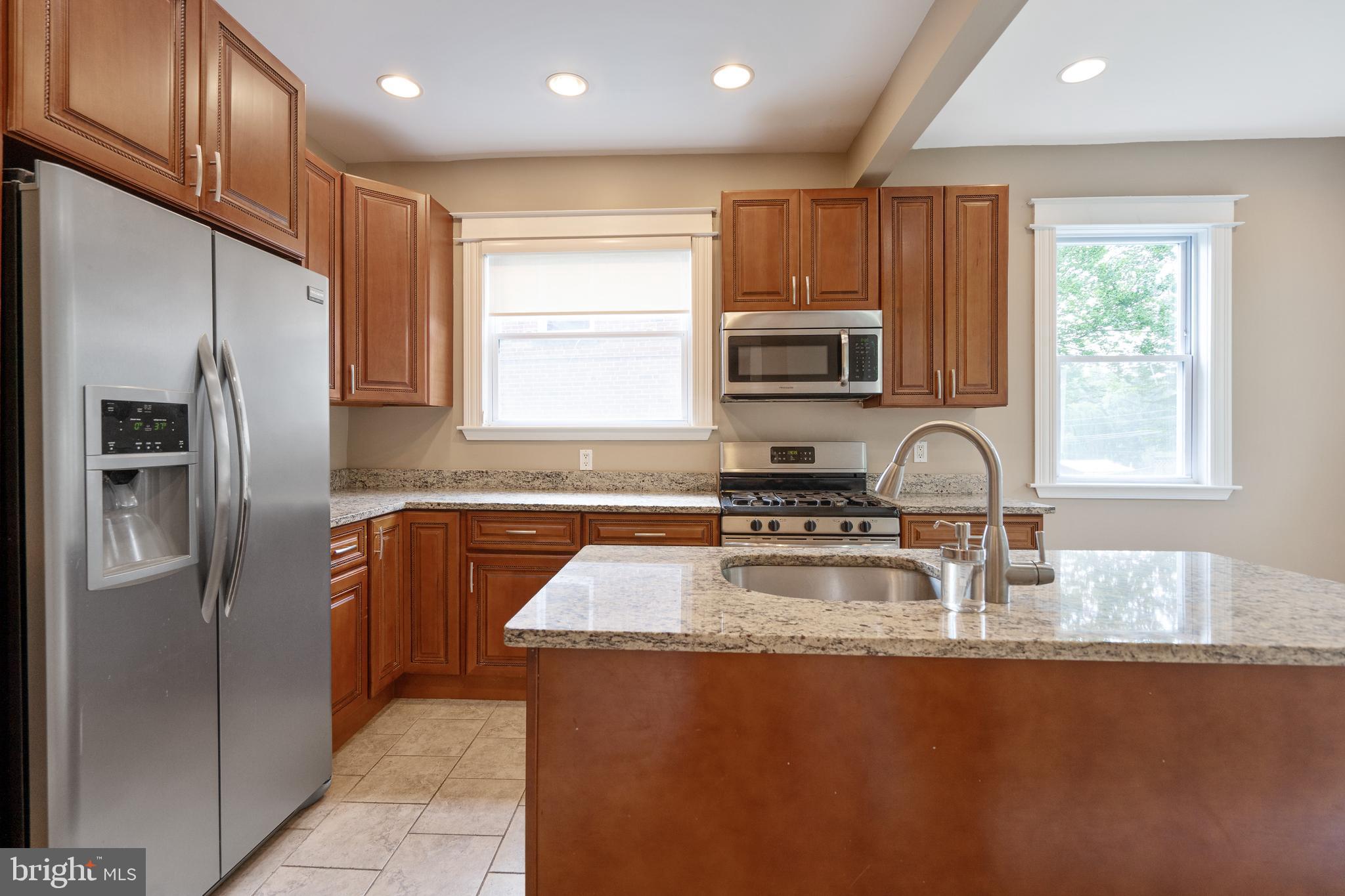 1955 Seminary Road Silver Spring, MD 20910 - Photo 14 of 41 a kitchen with kitchen island granite countertop a sink refrigerator and microwave