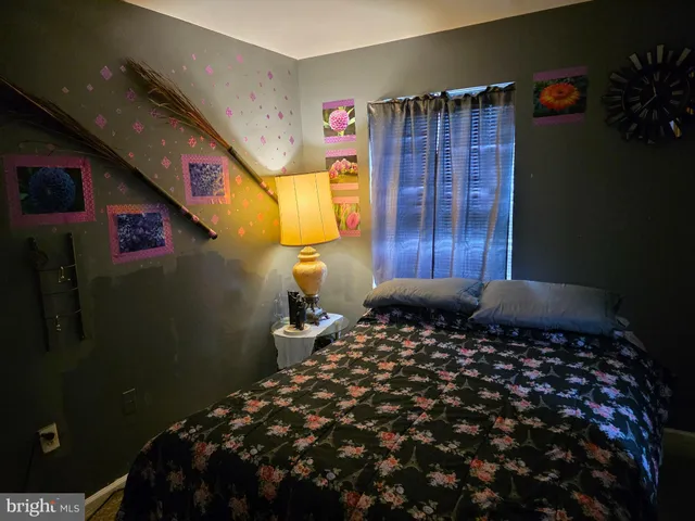a bedroom with a bed and a lamp on dresser