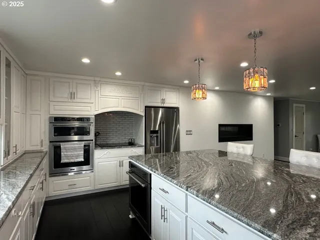 a kitchen with stainless steel appliances granite countertop a sink a stove and a refrigerator