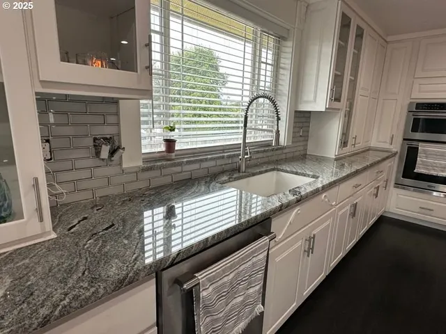a kitchen with granite countertop stainless steel appliances a sink and cabinets