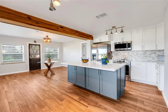 a living room with stainless steel appliances kitchen island granite countertop a sink cabinets and wooden floor