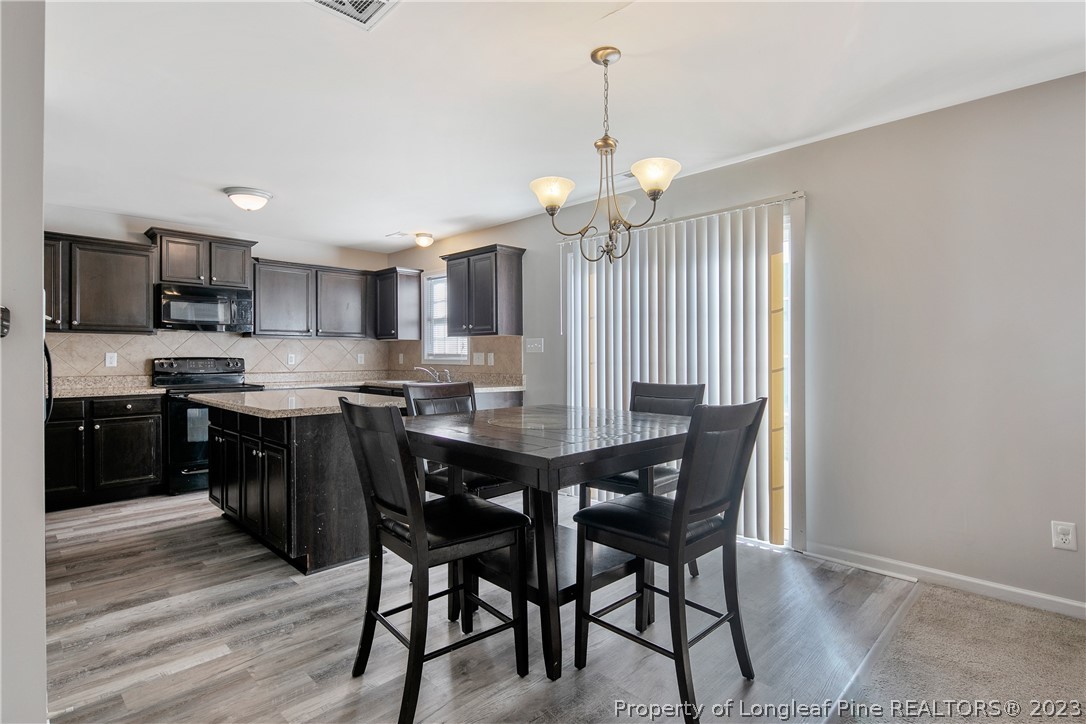 2040 Yellowbrick Road Fayetteville, NC 28314 - Photo 13 of 50 a kitchen with stainless steel appliances kitchen island granite countertop a table chairs sink and cabinets