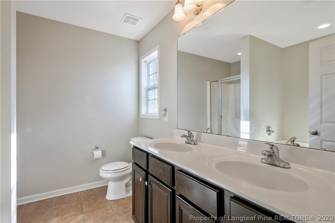 2040 Yellowbrick Road Fayetteville, NC 28314 - Photo 33 of 50 a bathroom with a double vanity sink toilet and a mirror