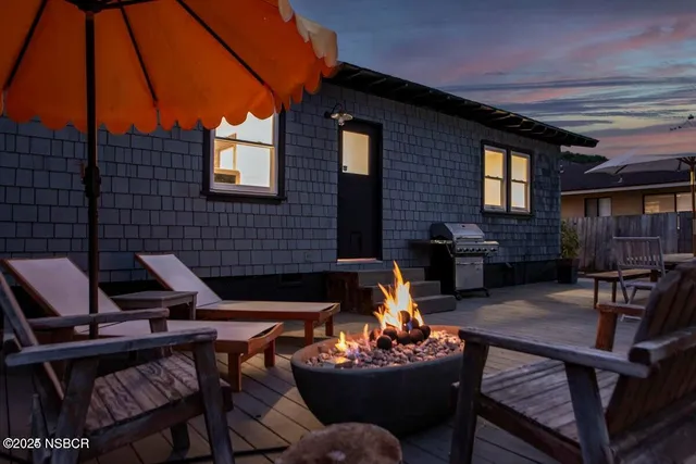 a backyard of a house with fire pit table and chairs