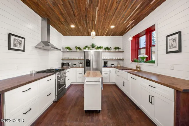 a large kitchen with stainless steel appliances granite countertop a lot of counter space and wooden floors