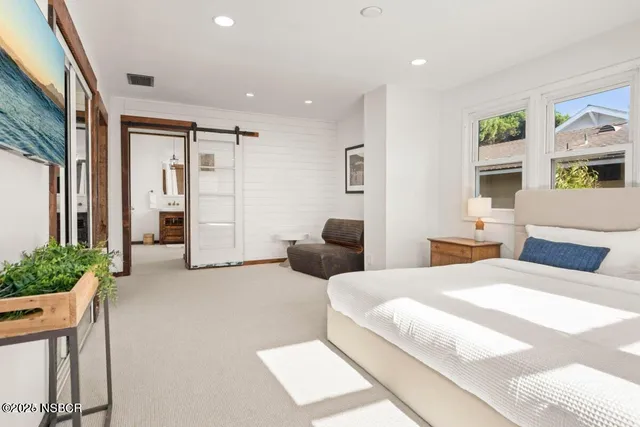 a bedroom with a bed large window and furniture