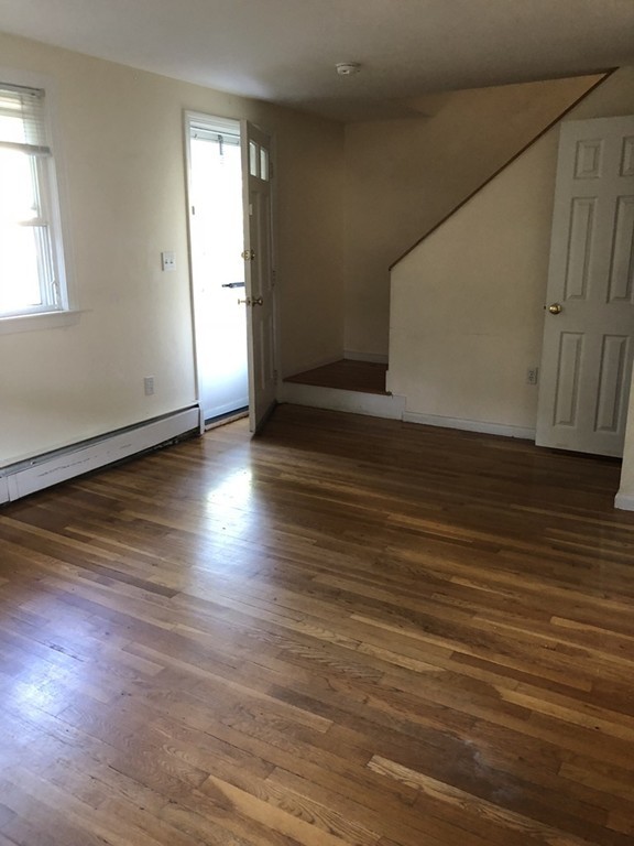 27 George Road, Unit 27 Winchester, MA 01890 - Photo 10 of 30 an empty room with wooden floor and windows with curtains