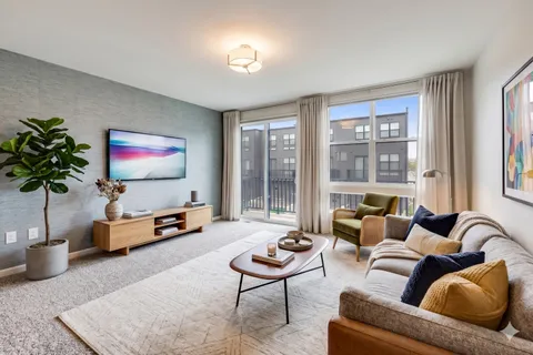 a living room with furniture floor to ceiling window and a flat screen tv