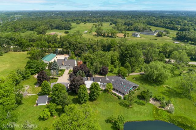 an aerial view of residential house with outdoor space and trees all around