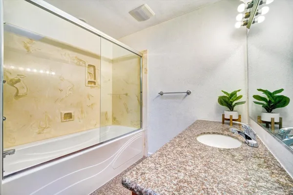 a bathroom with a granite countertop sink a mirror and a shower