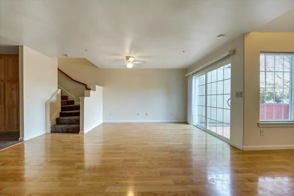 a view of an empty room with wooden floor and a window