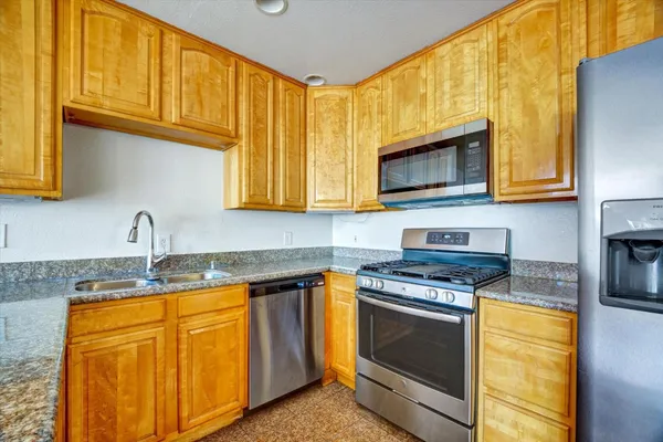 a kitchen with granite countertop wooden cabinets stainless steel appliances and a sink