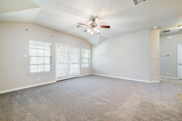 an empty room with a kitchen and a ceiling fan