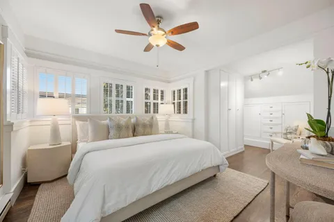 a bedroom with a large bed a chandelier and a potted plant
