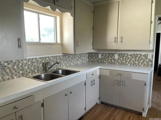 a view of cabinets a sink and dishwasher with wooden floor