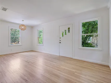 a view of an empty room with wooden floor and a window